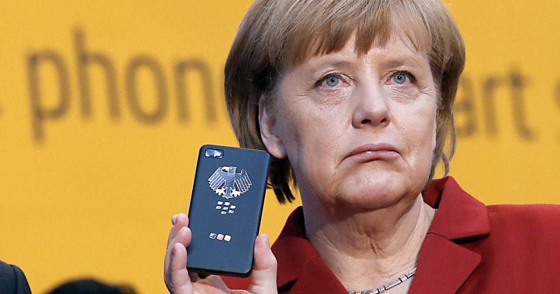 File photo of German Chancellor Merkel holding a smartphone featuring high security Secusite software in Hanover...German Chancellor Angela Merkel (R) reacts as she holds a BlackBerry Z10 smartphone featuring high security Secusite software, used for governmental communication, at the booth of Secusmart during her opening tour with Poland's Prime Minister Donald Tusk on the CeBit computer fair in Hanover in this March 5, 2013 file photo. Germany's Foreign Minister has summoned the United States' ambassador to Germany, John B. Emerson, to discuss information obtained by Berlin that the U.S. may have monitored Merkel's mobile phone, a government spokesman said on October 24, 2013.    REUTERS/Fabrizio Bensch/Files (GERMANY - Tags: BUSINESS SCIENCE TECHNOLOGY POLITICS)