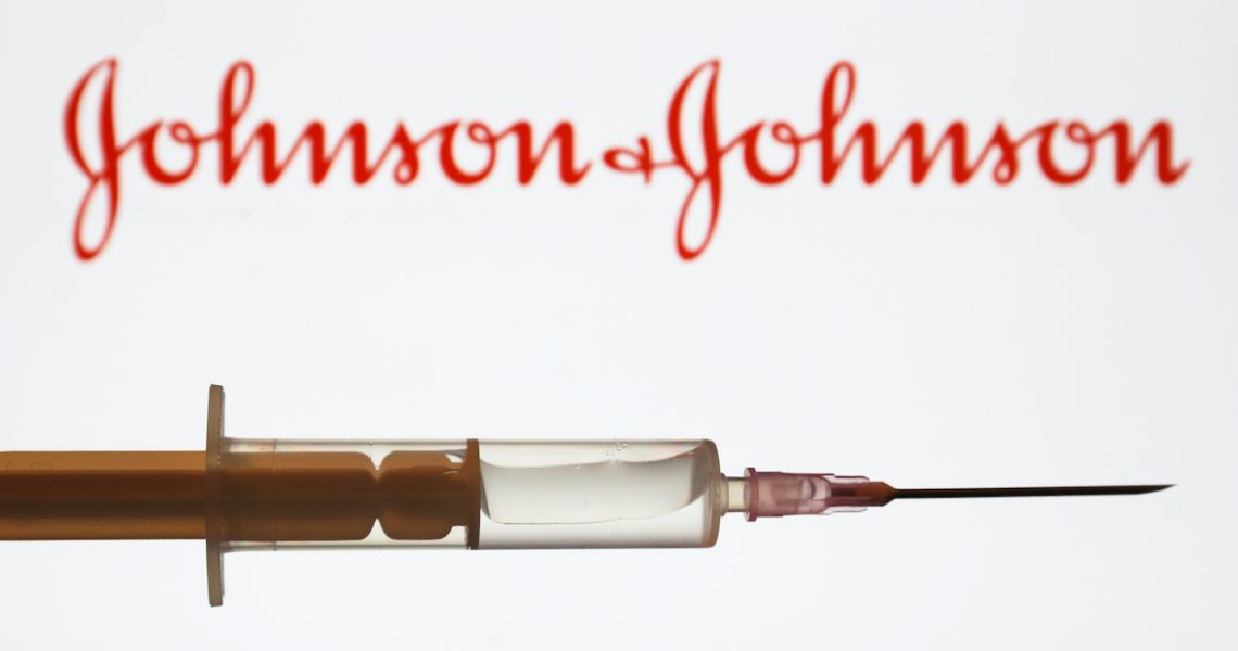 Medical syringe is seen with Johnson & Johnson company logo displayed on a screen in the background in this illustration photo taken in Poland on June 16, 2020. (Photo Illustration by Jakub Porzycki/NurPhoto)