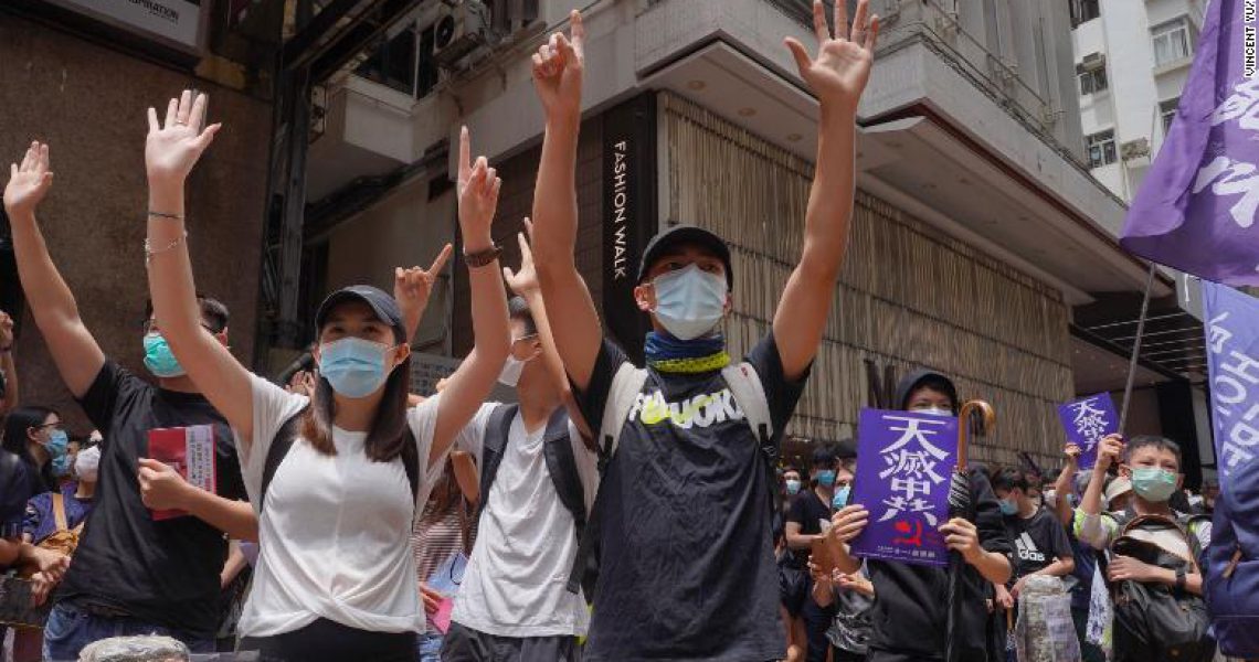 Protesters gesture with five fingers, signifying the "Five demands - not one less" as hundreds of protesters march along a downtown street during a pro-democracy protest against Beijing's national security legislation in Hong Kong, Sunday, May 24, 2020. Hong Kong's pro-democracy camp has sharply criticised China's move to enact national security legislation in the semi-autonomous territory. They say it goes against the "one country, two systems" framework that promises the city freedoms not found on the mainland. (AP Photo/Vincent Yu)