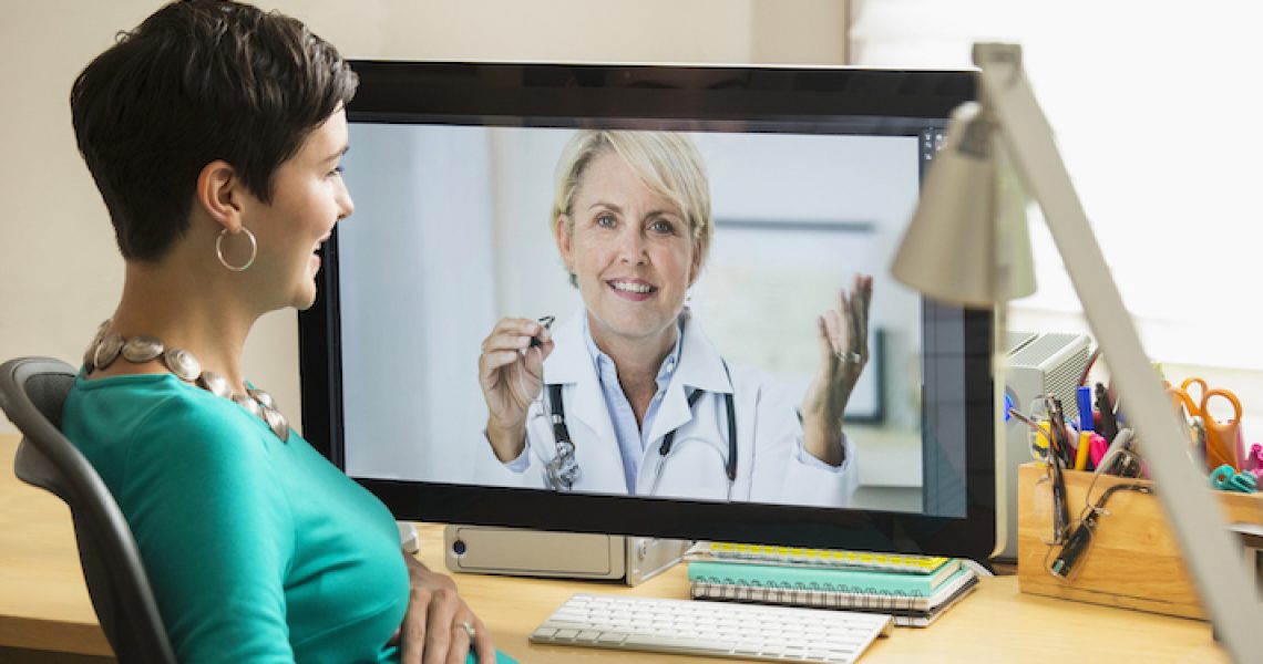 Pregnant mixed race businesswoman video chatting with doctor